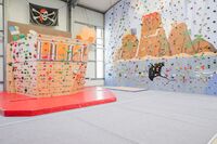 Boulderblock für Kinder, sieht aus wie ein Schiffsbug. Dahinter einer Kletterwand, bemalt mit Untwerwasserszenen.