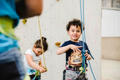 Junge und Mädchen mit Kletterausrüstung vor einer Wand