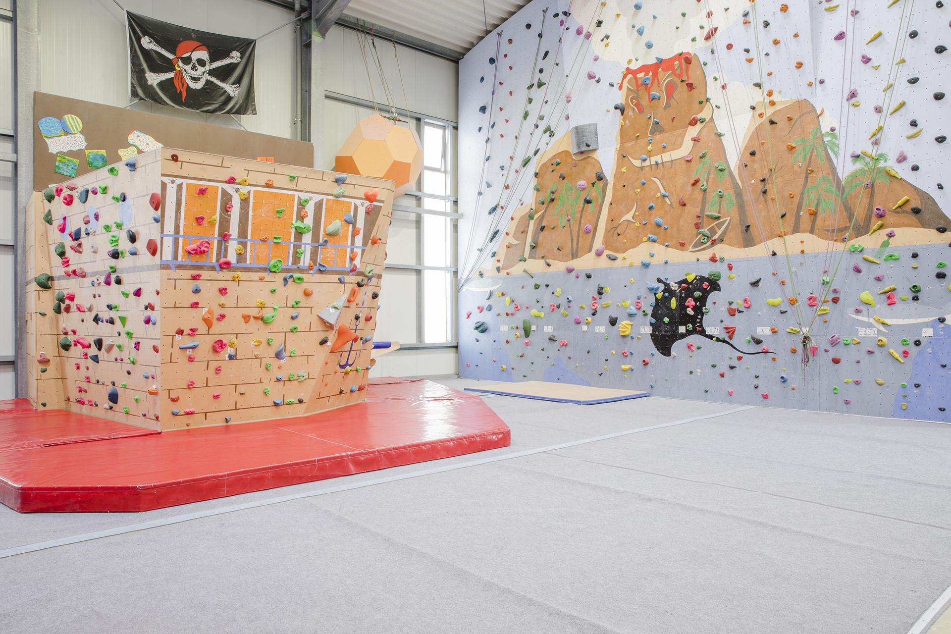 Boulderblock für Kinder, sieht aus wie ein Schiffsbug. Dahinter einer Kletterwand, bemalt mit Untwerwasserszenen.